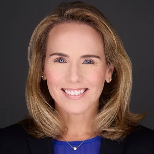 Cathy professional headshot smiling warmly in blue top against dark gray studio backdrop, client testimonial for Loudoun County headshots