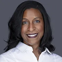 Kahni professional headshot with genuine smile in white top against gray studio background, client review for Loudoun County headshot photographer