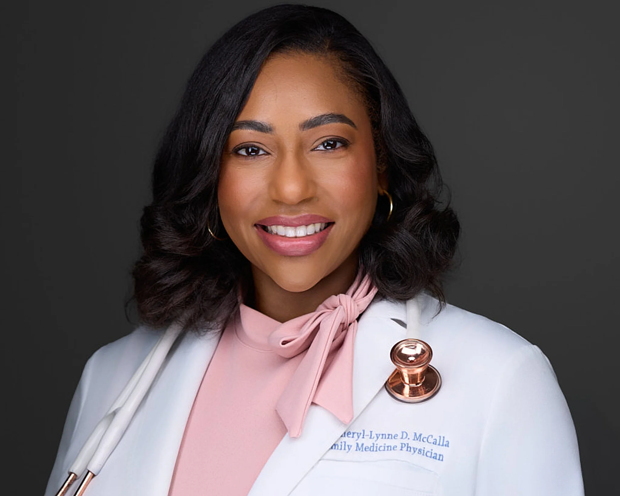 Medical professional headshot of Dr. Cheryl-Lynne McCalla in white coat with stethoscope against neutral gray background